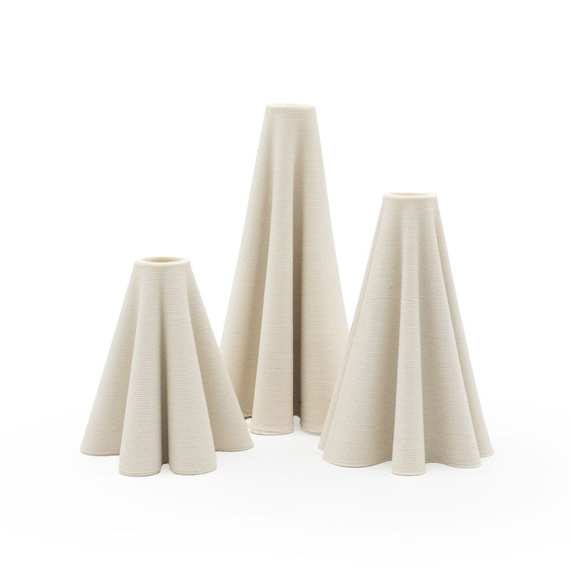 Three 3D printed ceramic cone-shaped candleholders with a ripple pattern on a white background