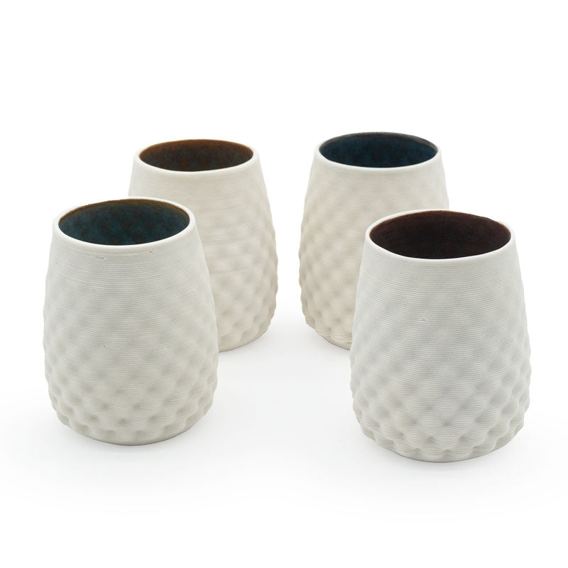 Four porcelain drinking cups with a stemless dot pattern, with a dark interior design on a white background