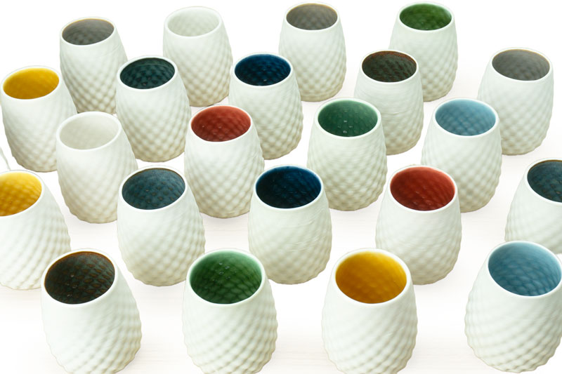 Set of white porcelain drinking cups with a stemless dot pattern, with colored interior designs on a white background