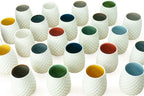 Set of white porcelain drinking cups with a stemless dot pattern, with colored interior designs on a white background