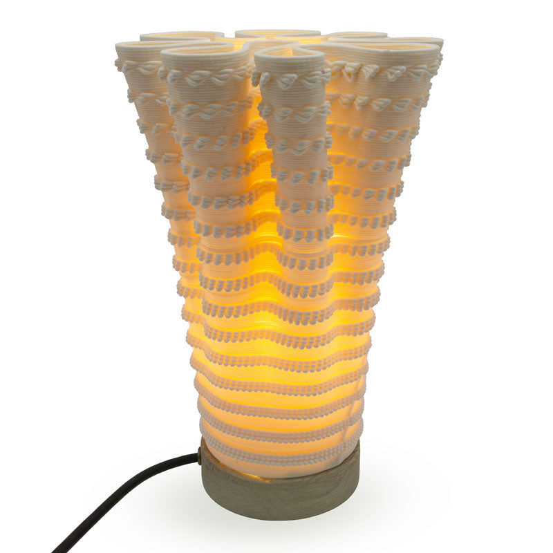 Coral-like textured translucent porcelain table lamp with a warm glow on a white background