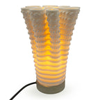 Coral-like textured translucent porcelain table lamp with a warm glow on a white background