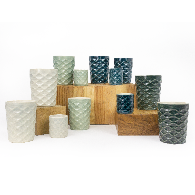 Collection of textured ceramic cups in various colors on a white background