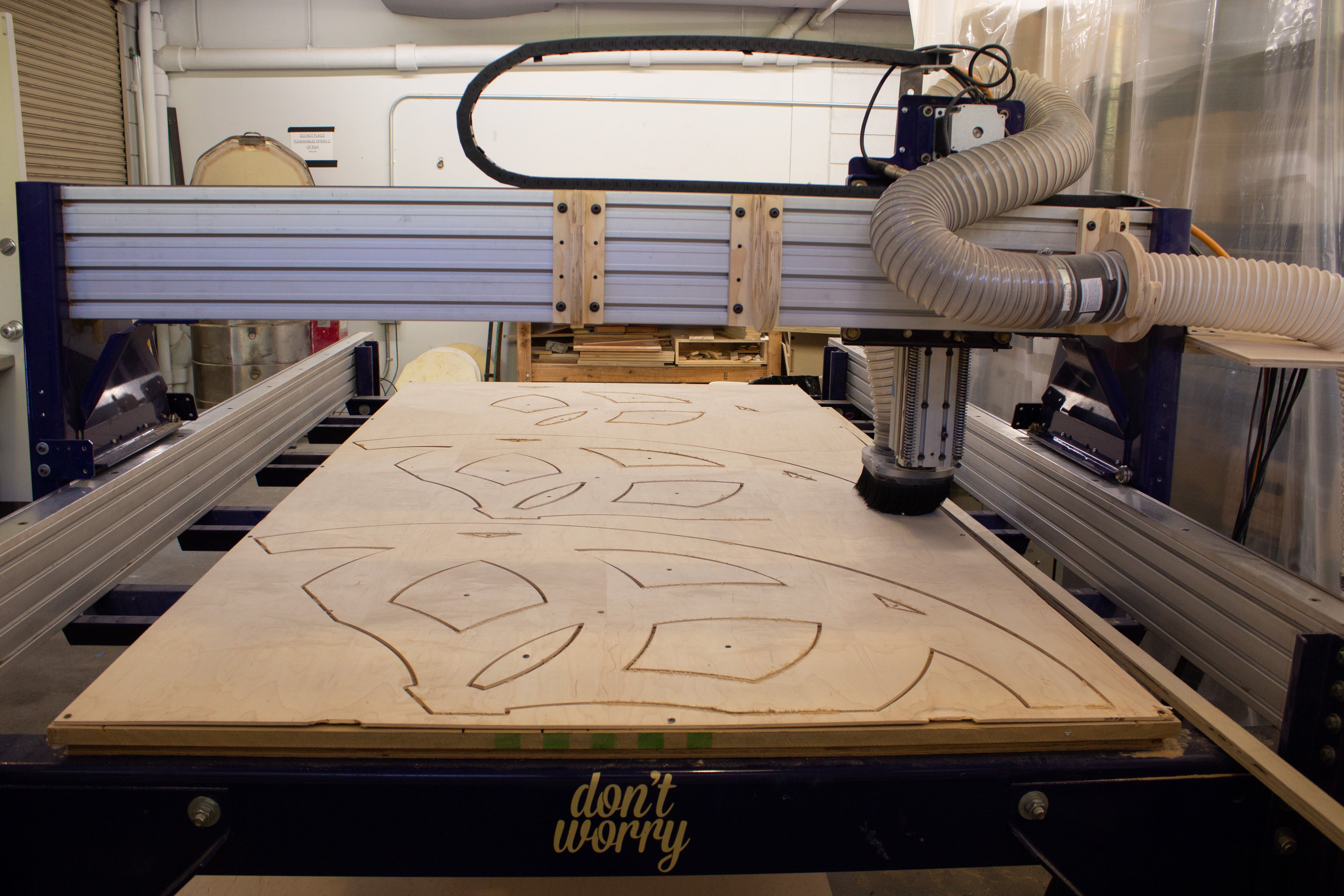 CNC machine with a wooden board featuring laser cut shapes in the studio.