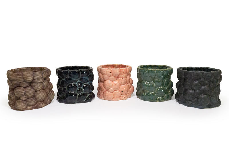 Five 3D printed ceramic planter with a bubble pattern on a white background, one brown, black, pink, green, and matte black