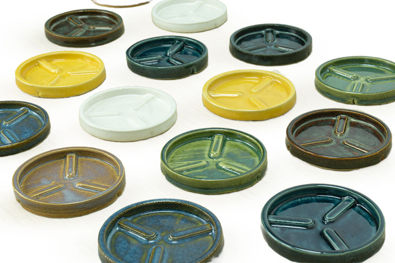 an array of ceramic planter trays in yellow, white, turquoise, brown, and green