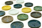 an array of ceramic planter trays in yellow, white, turquoise, brown, and green