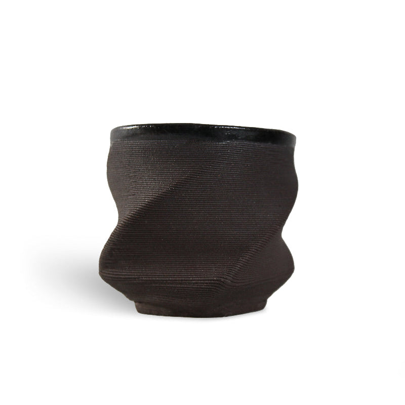 Black 3D printed ceramic cup with a textured eternity pattern, on a white background