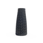 Tall matte black textured 3D printed ceramic vase with a zig zag taper, on a white background