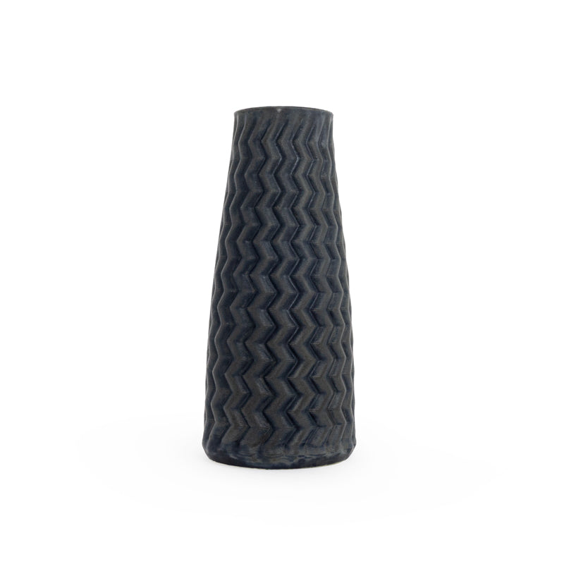 Tall matte black textured 3D printed ceramic vase with a zig zag taper, on a white background